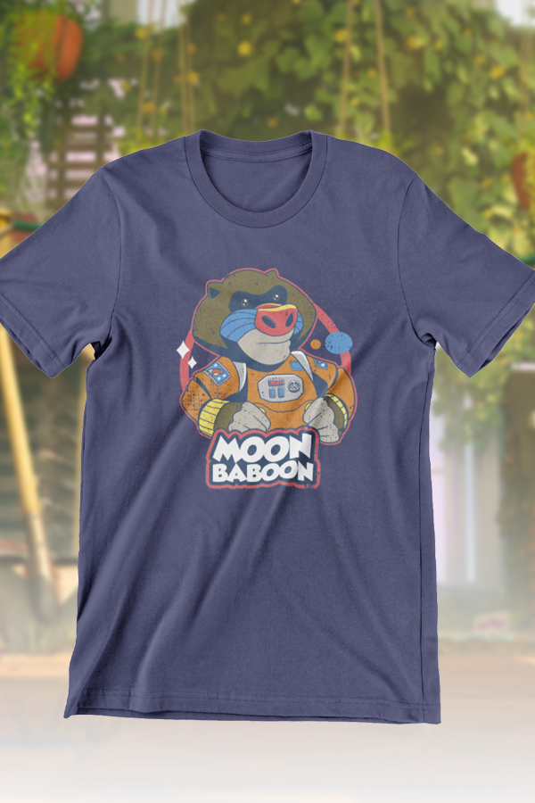 Image shows It Takes Two Moon Baboon Tee (blue) facing front. Moon Baboon has brown fur and, like an mandrill, he has blue and red markings on his face. He wears an orange jumpsuit with yellow cuffs and buttons. Moon Baboon has two patches with pictures of rockets on both his arms and one with his name on his chest. He also wears a white pack with his name printed on the back.